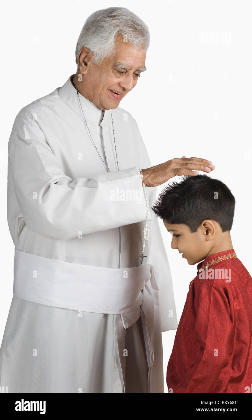 Priest blessing a boy and smiling Stock Photo Alamy