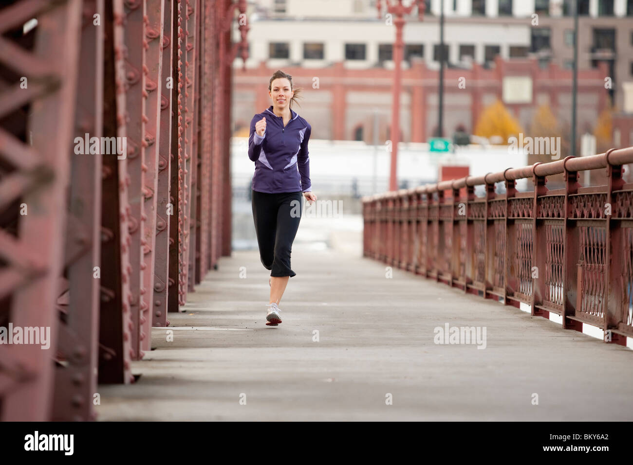 An athletic female in a purple jacket running along a bridge in Portland, Oregon. Stock Photo
