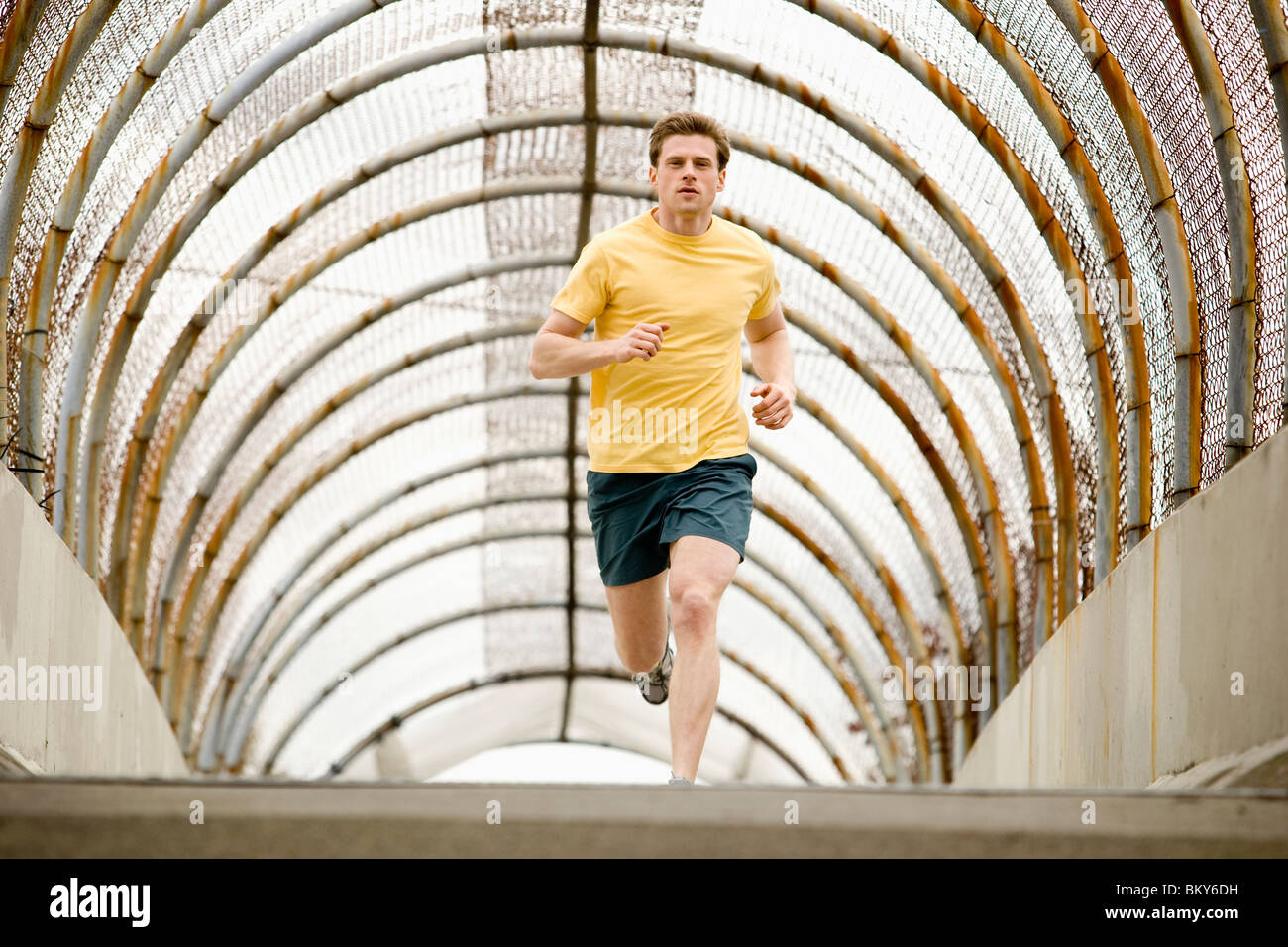An athletic male jogging through a pedestrain overpass Stock Photo - Alamy