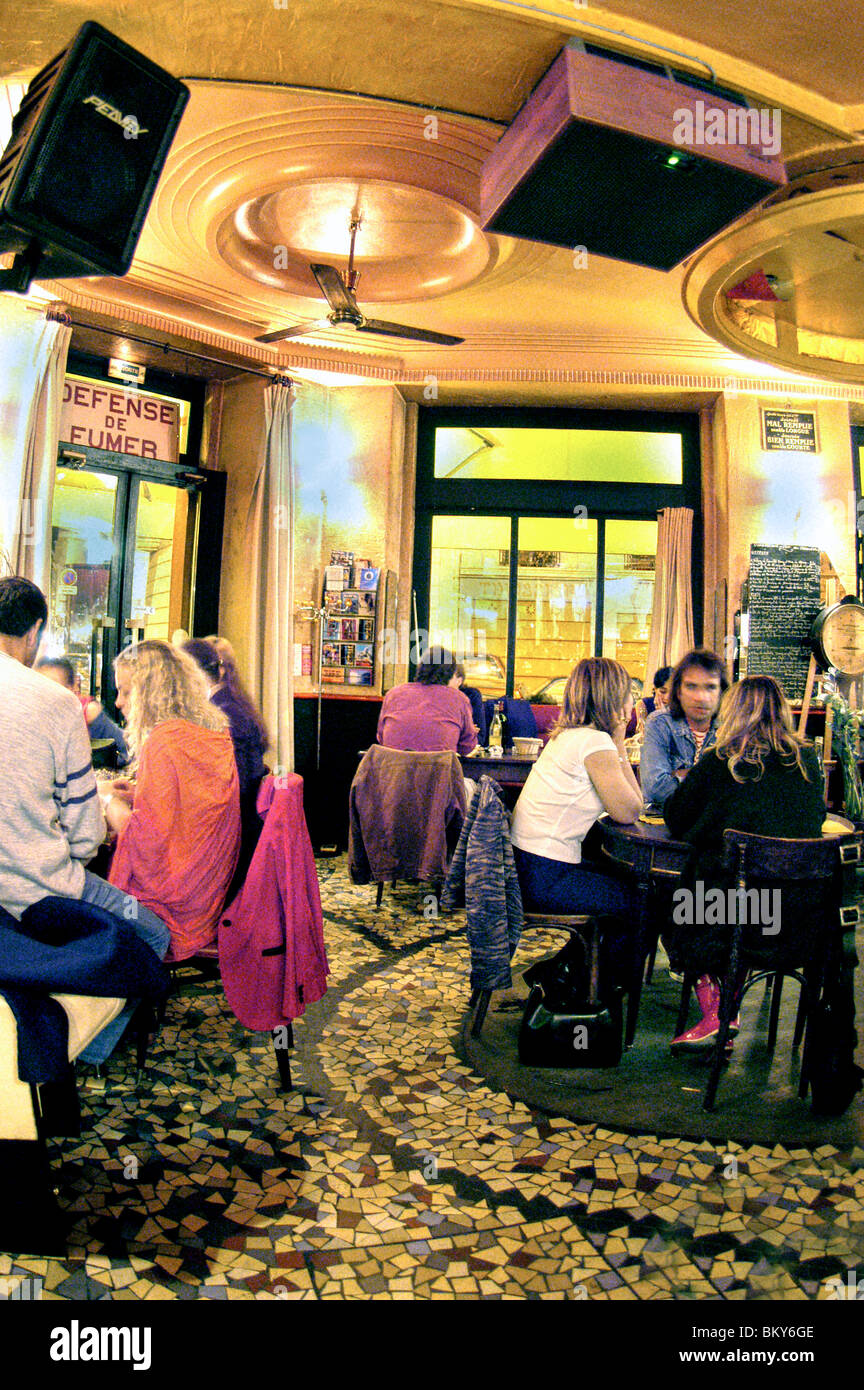 PARIS, France -  Group People Sitting at Tables, Sharing Meals inside Café Bistro Restaurant 'Polichinelle Café', Stock Photo