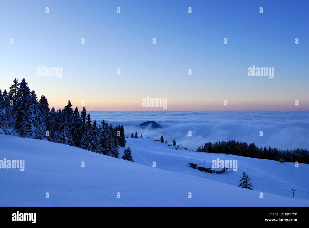 Snow-covered alpine hut above fog bank at dusk, Kampenwand, Chiemgau Alps, Chiemgau, Bavaria, Germany Stock Photo