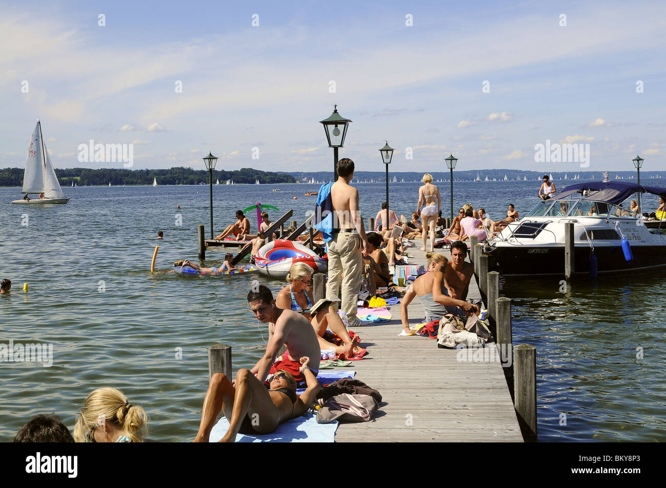 People sunbathing on jetty at lake Starnberg, Seeshaupt, Bavaria