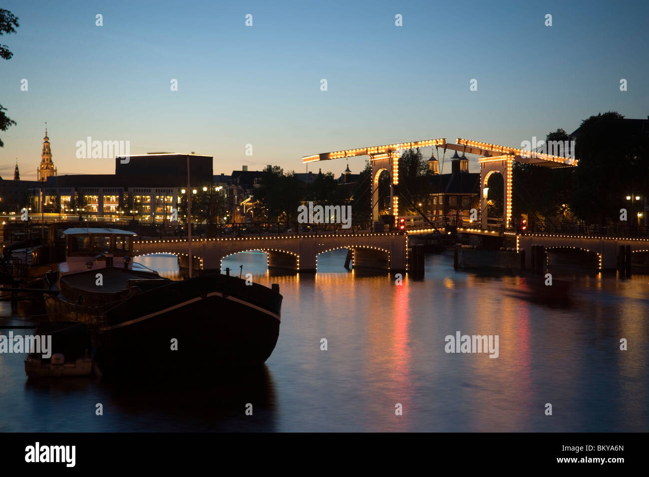 Boats, Magere Brug, Amstel, View over illuminated Magere Brug Skinny Bridge, to Stopera and Zuiderkerk at night, Amsterdam, Holl Stock Photo