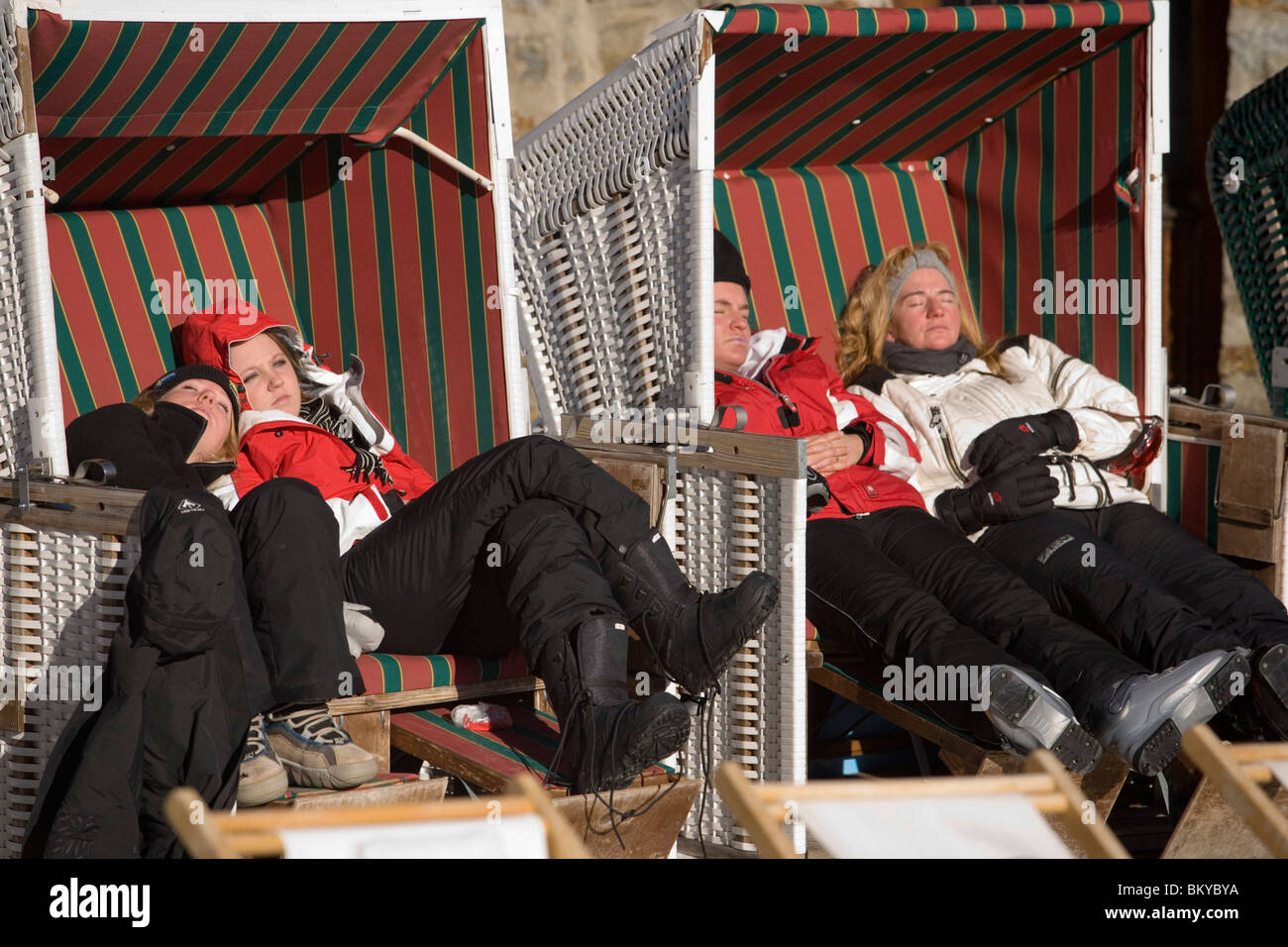 People sitting and sunbathing in roofed wicker beach chairs at terrace of the Popcorn Plaza, a snowbar at Laengfluh, Saas-Fee, V Stock Photo