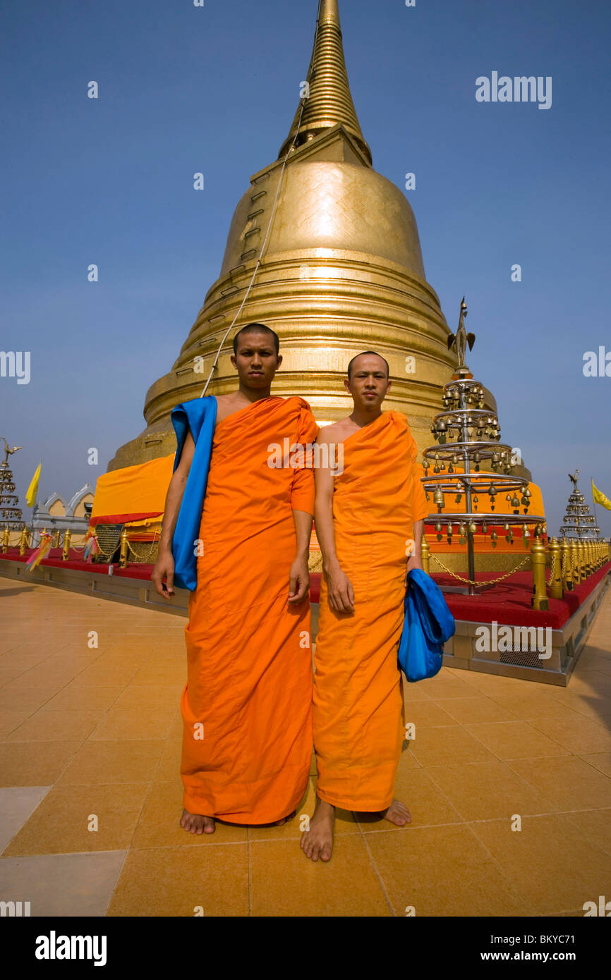 Two monks in front of gilded Chedi, housed a Buddha relic of the Wat Saket on the Golden Mount, Bangkok, Thailand Stock Photo