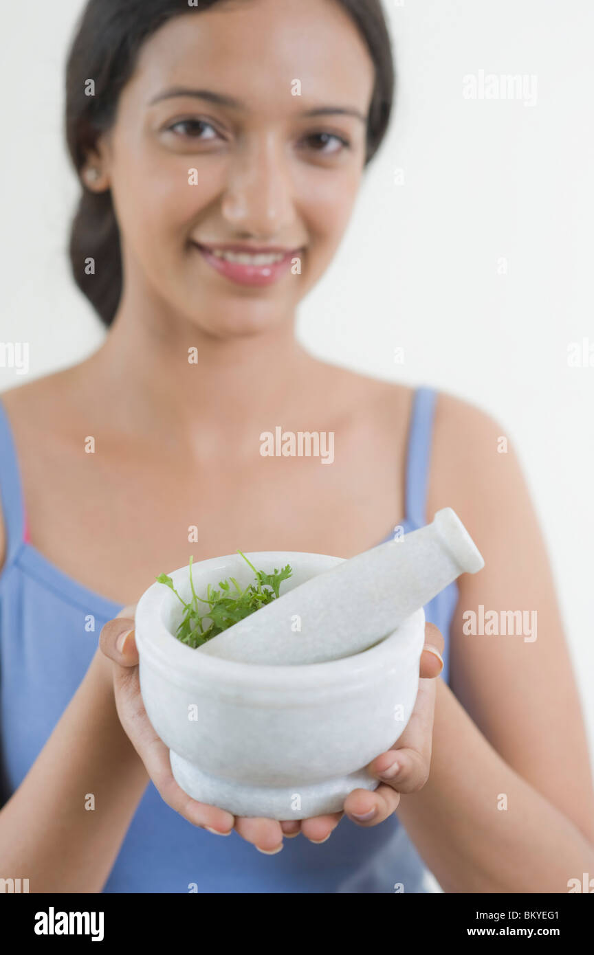 Woman holding a mortar and pestle with cilantro Stock Photo