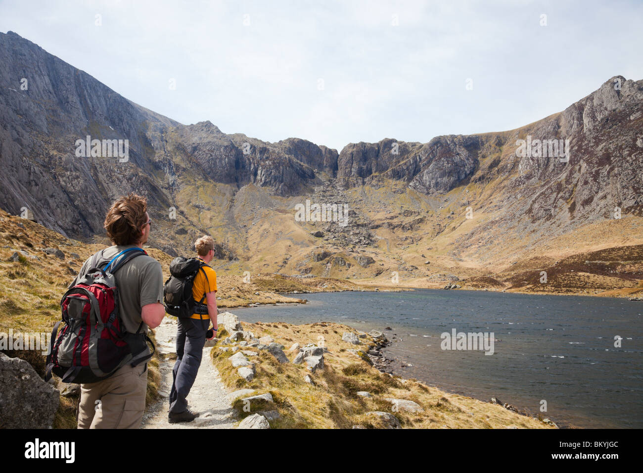 Two Millennial male hikers by Llyn Idwal looking at Devil's Kitchen in mountains of Snowdonia National Park. Cwm Idwal Ogwen North Wales UK Britain Stock Photo