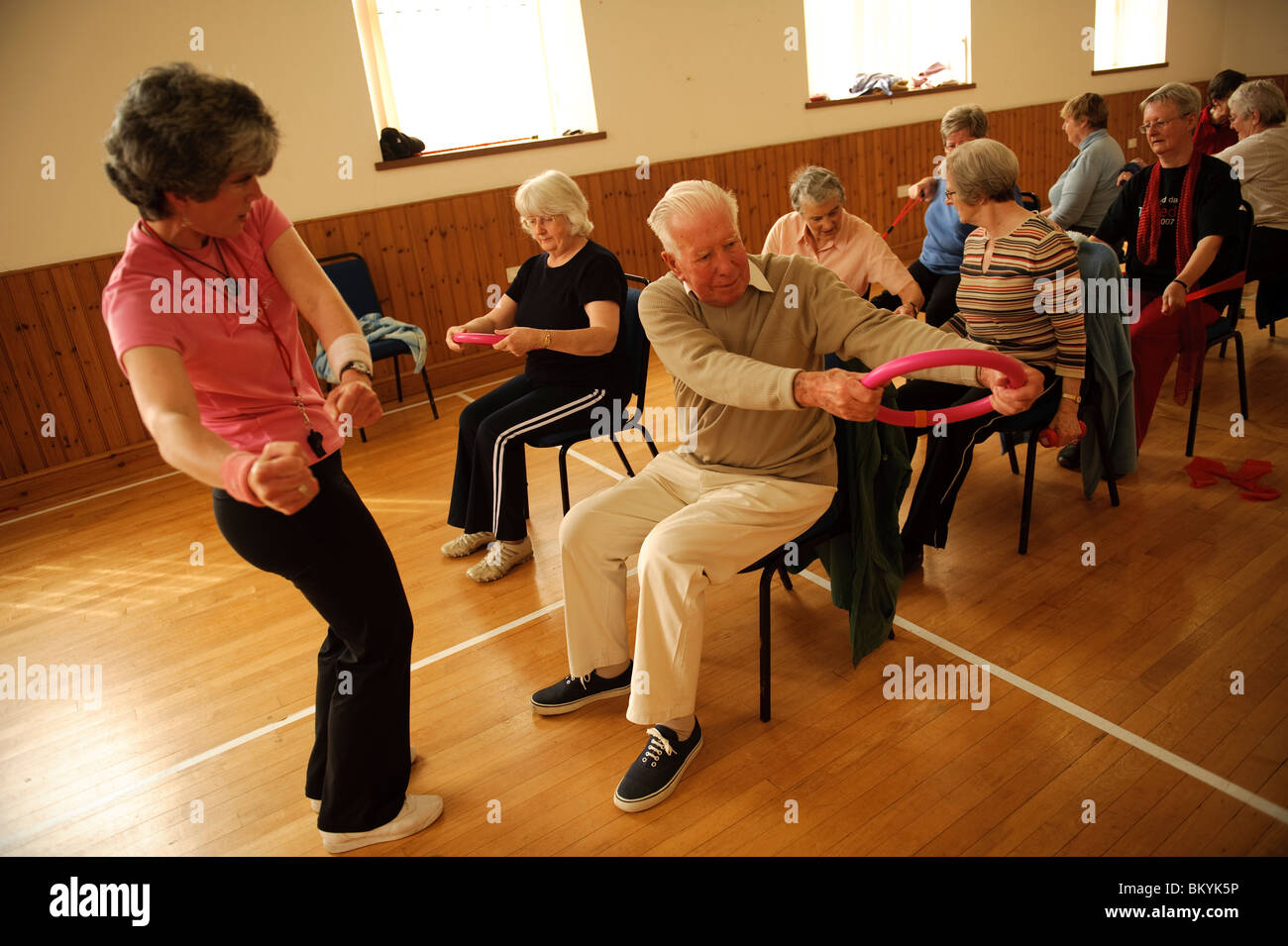 A group of fit active senior citizens participating in lowimpact chair aerobics class in a