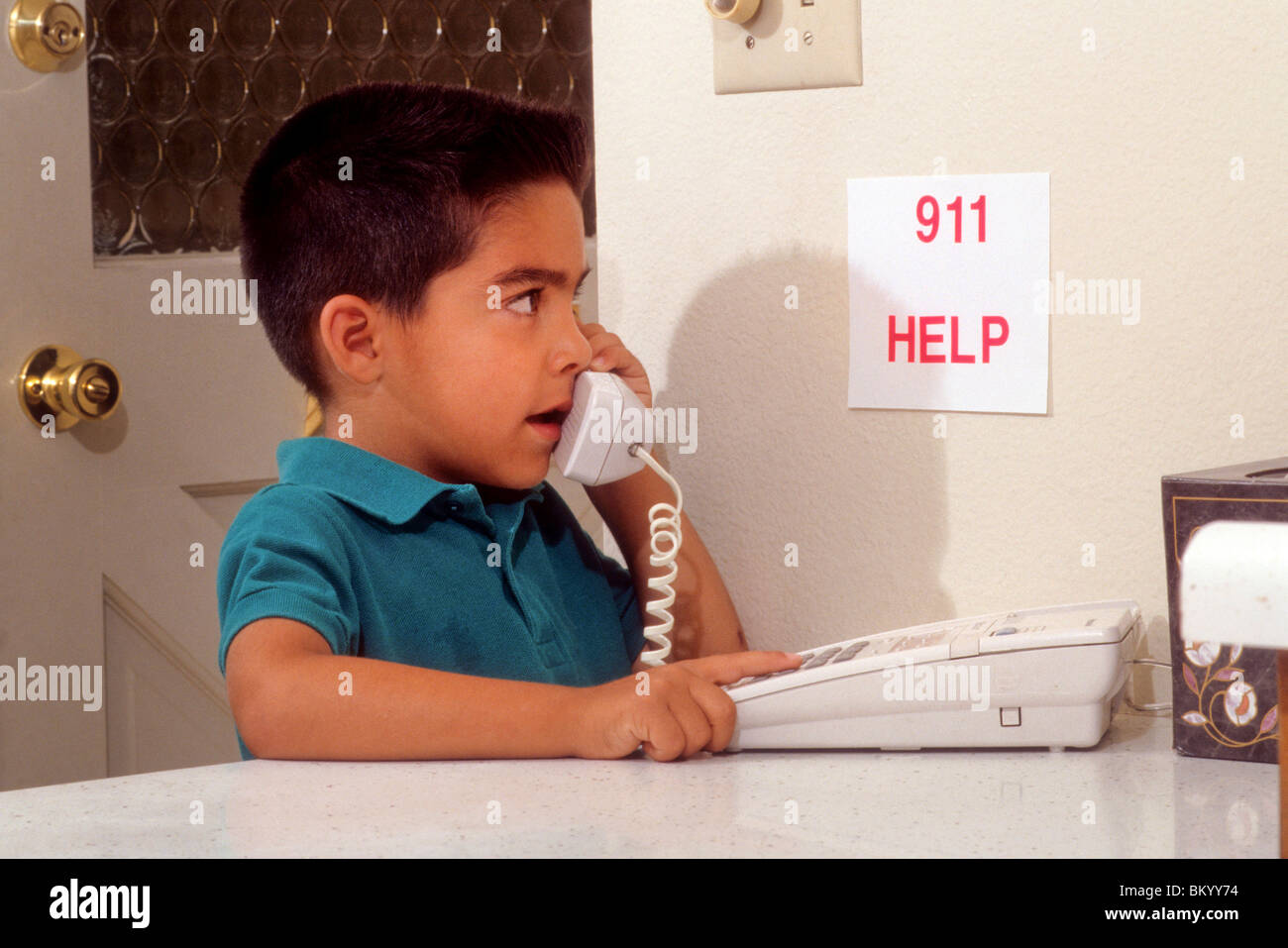 Young Hispanic boy calls 9-1-1 911 for help in emergency serious responsible response paramedic firefighter Stock Photo