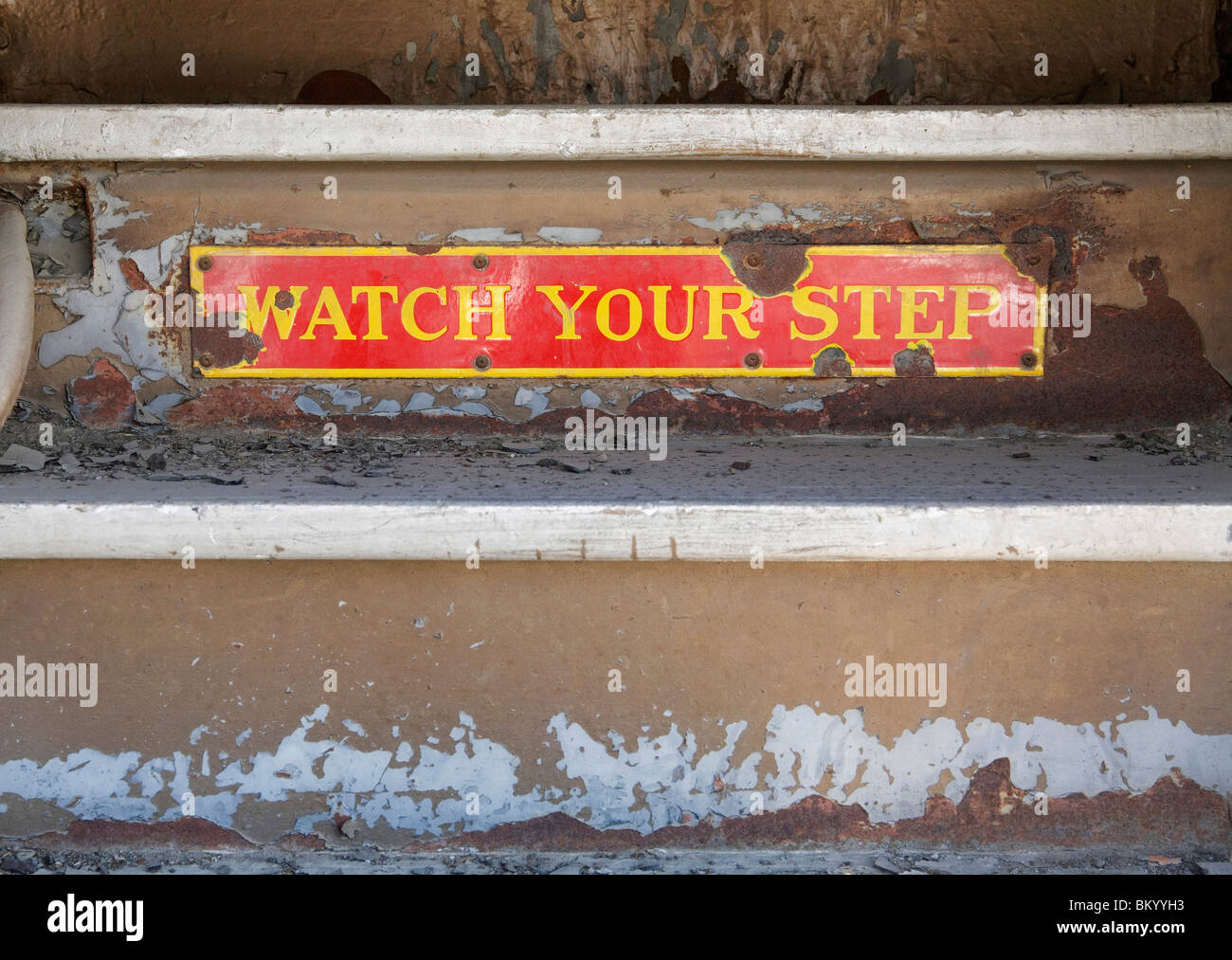 rusty old sign with words watch your step on train steps Stock Photo