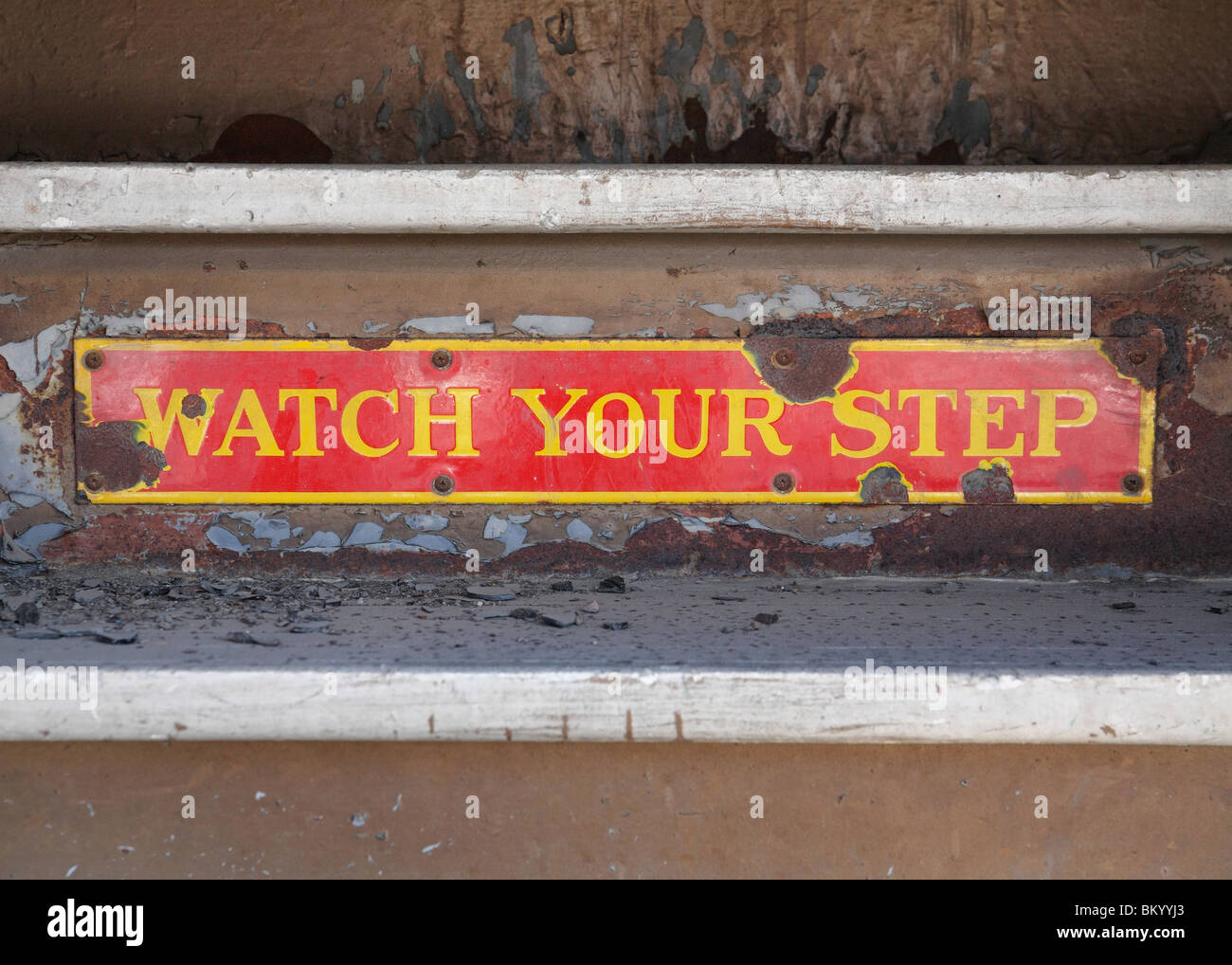 rusty old sign saying watch your step on train steps Stock Photo