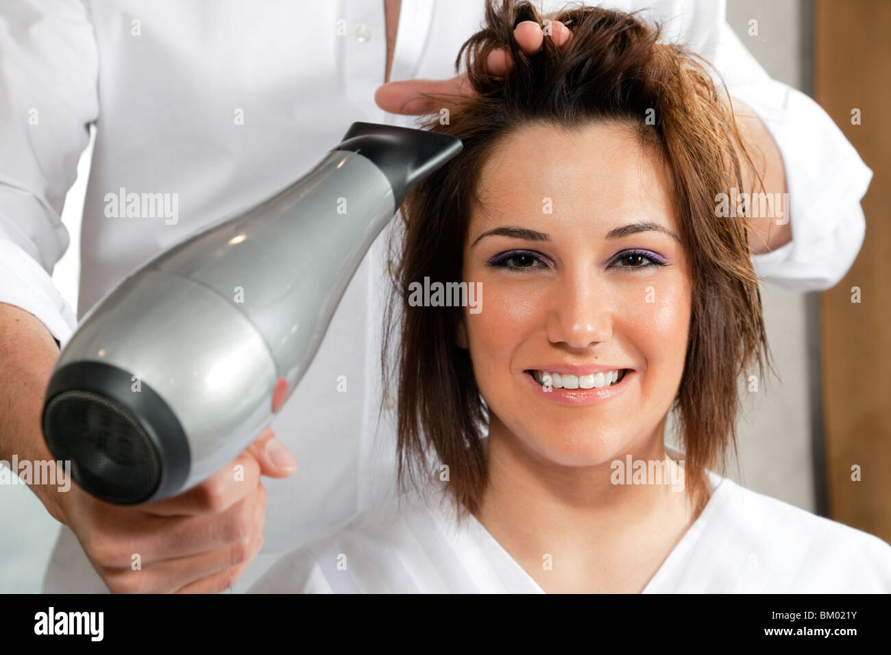cropped view of hairstylist drying woman hair. Front view Stock Photo
