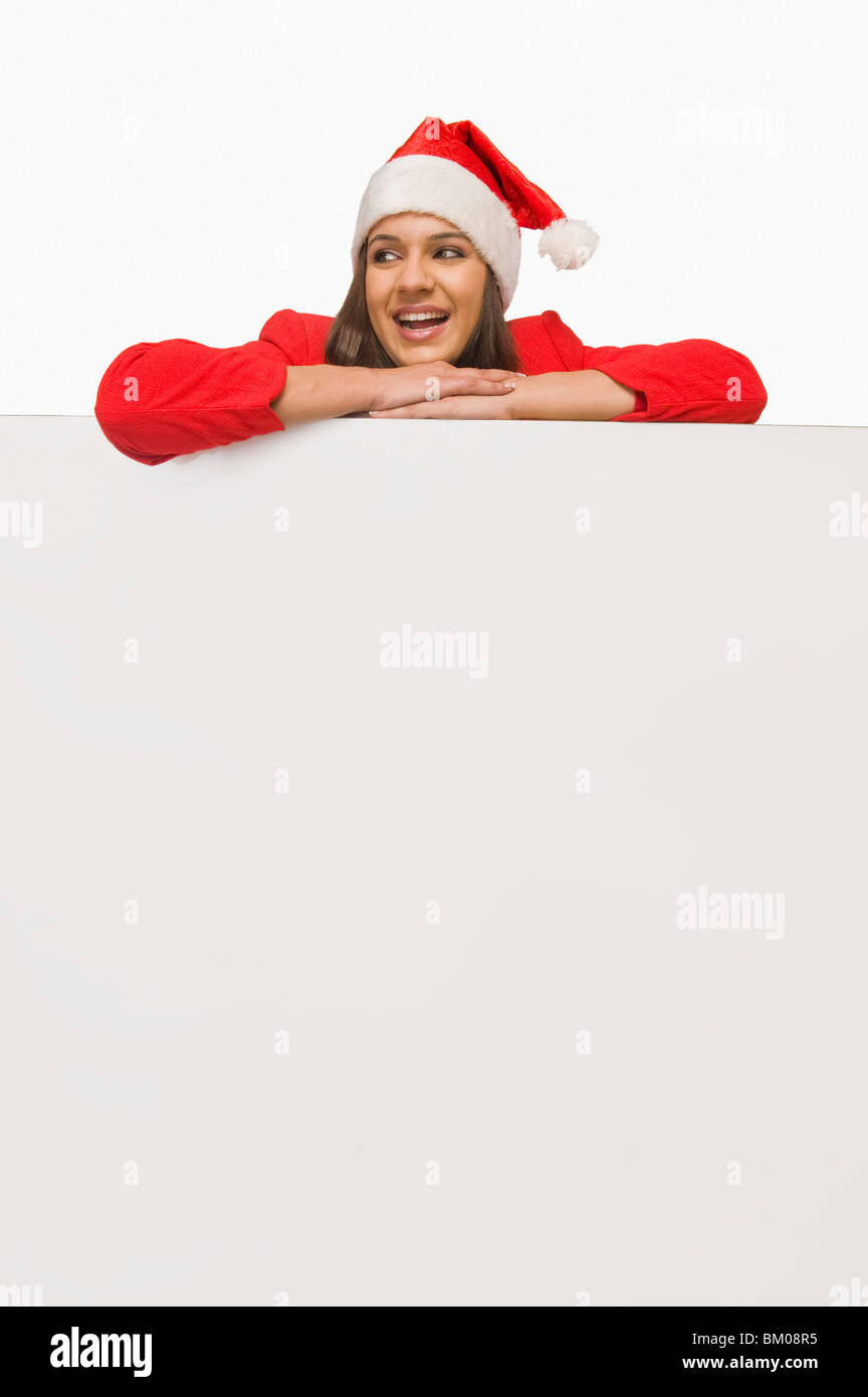 Woman in Santa costume leaning over a white board and smiling Stock
