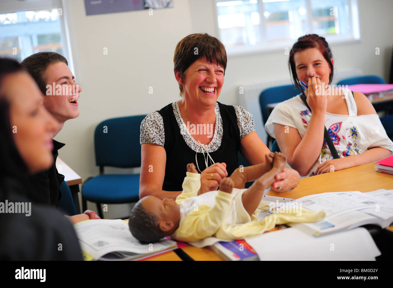 A teacher talking to pupils about motherhood and having a baby with a doll Stock Photo