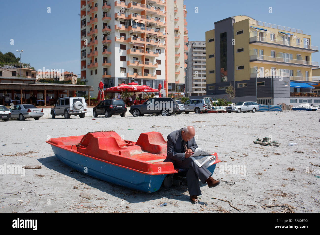 An old man reads newspaper on the beach in Durres, Albania. Stock Photo