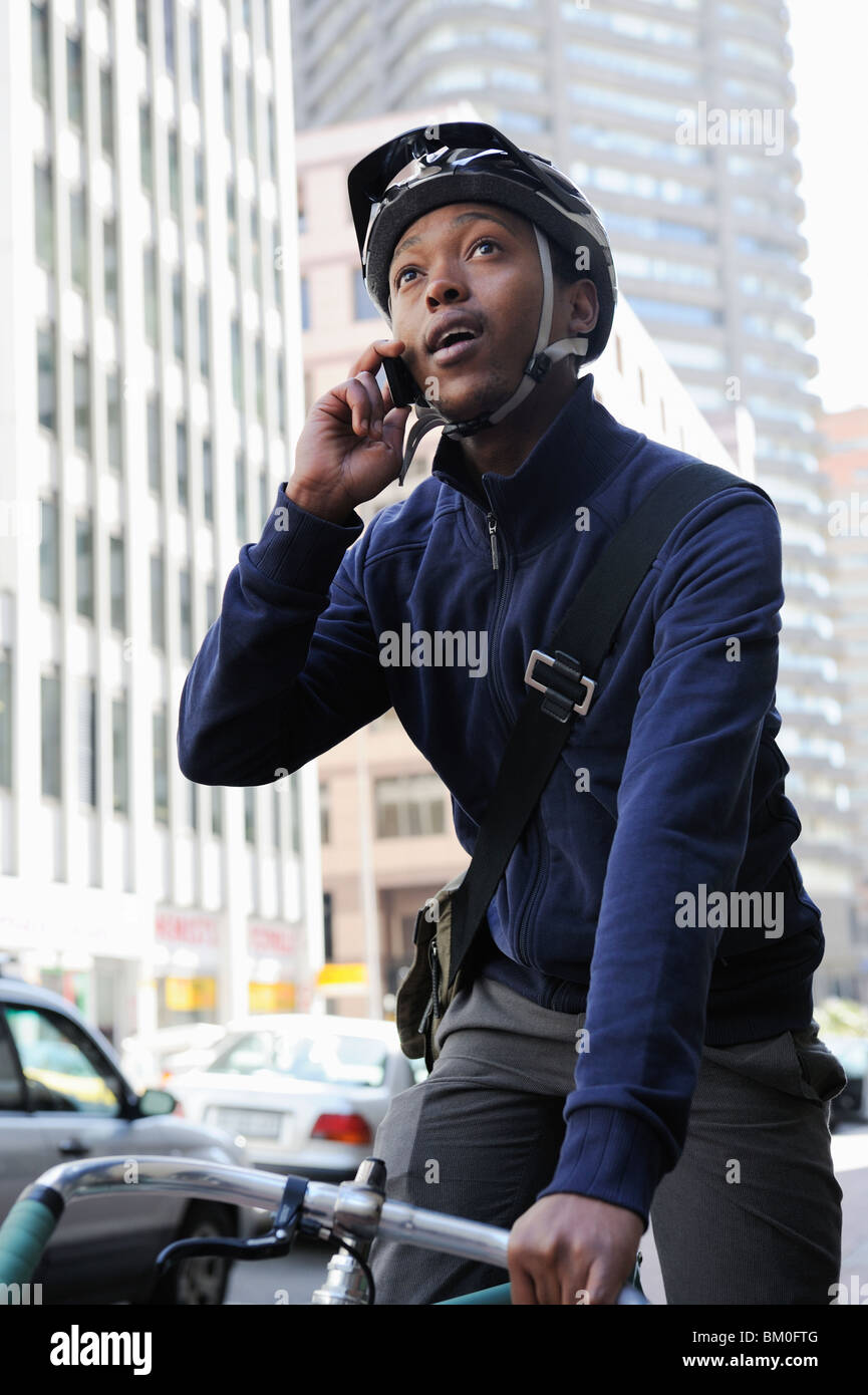 Young man on bicycle using mobile phone, Cape Town, Western Cape Province, South Africa Stock Photo