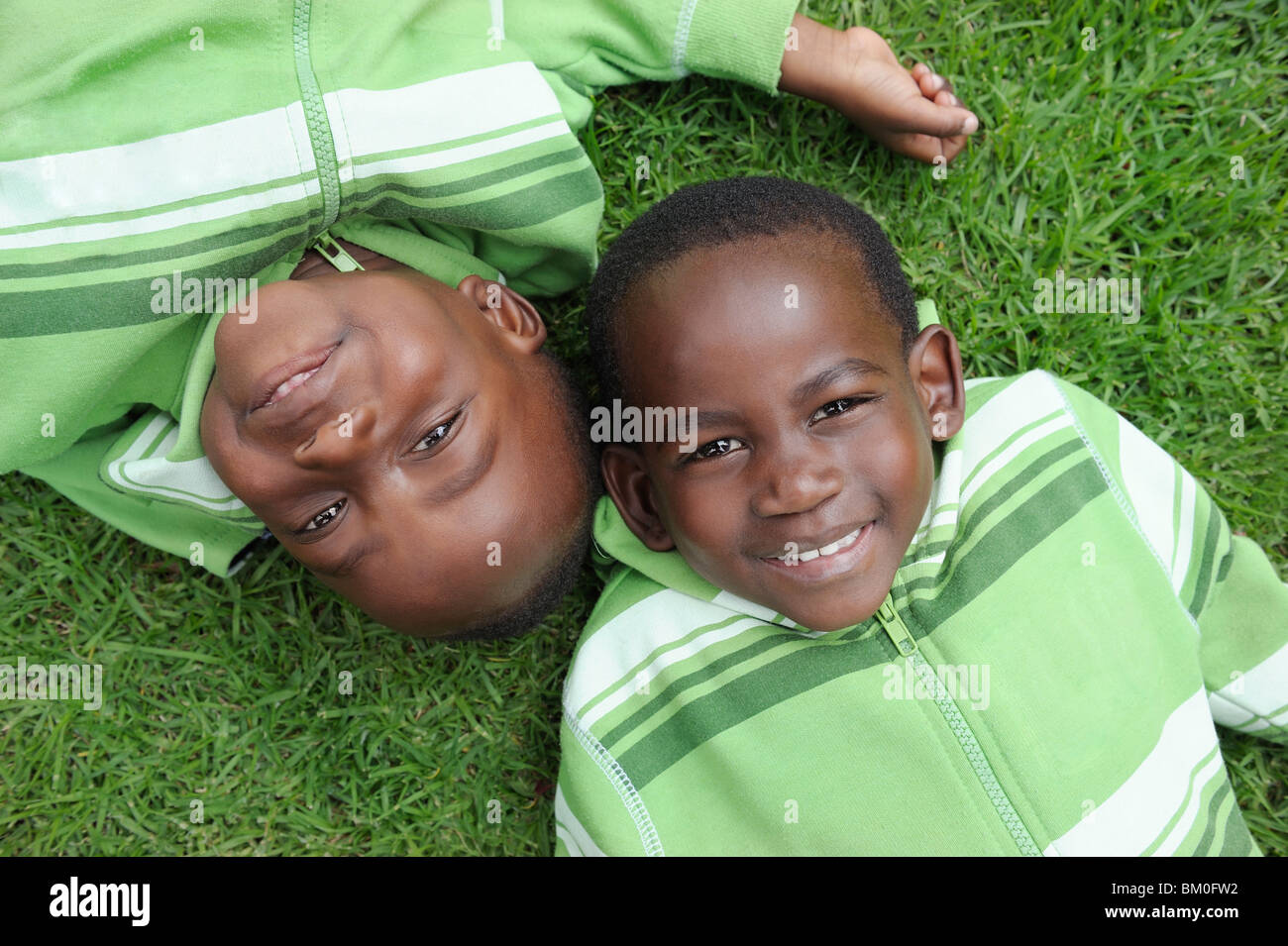 Twin brothers (2-3) lying on grass, Cape Town, Western Cape Province, South Africa Stock Photo