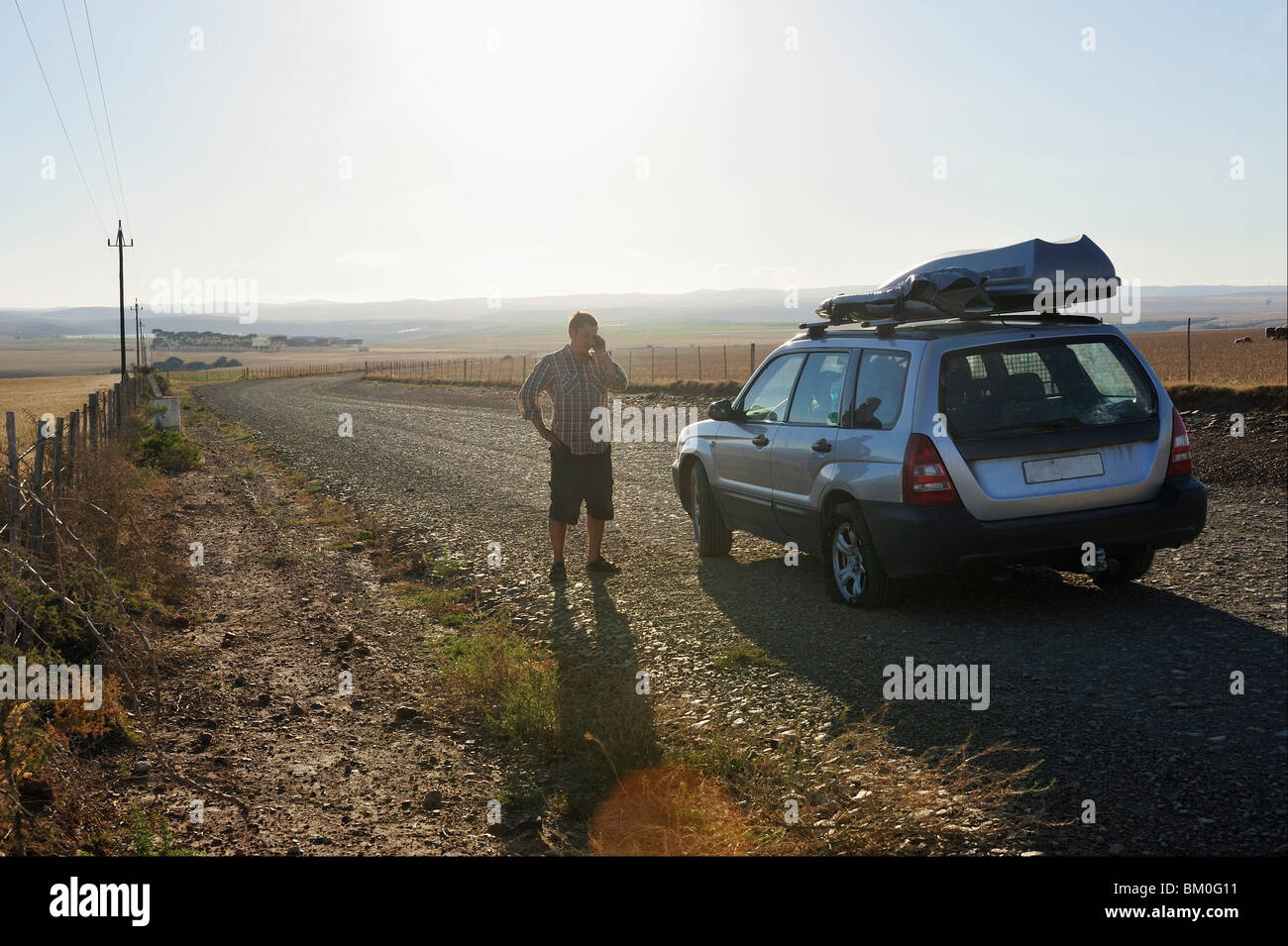 Man with flat tire on remote road, calling for help, near Malgas, Western Cape Province, South Africa Stock Photo