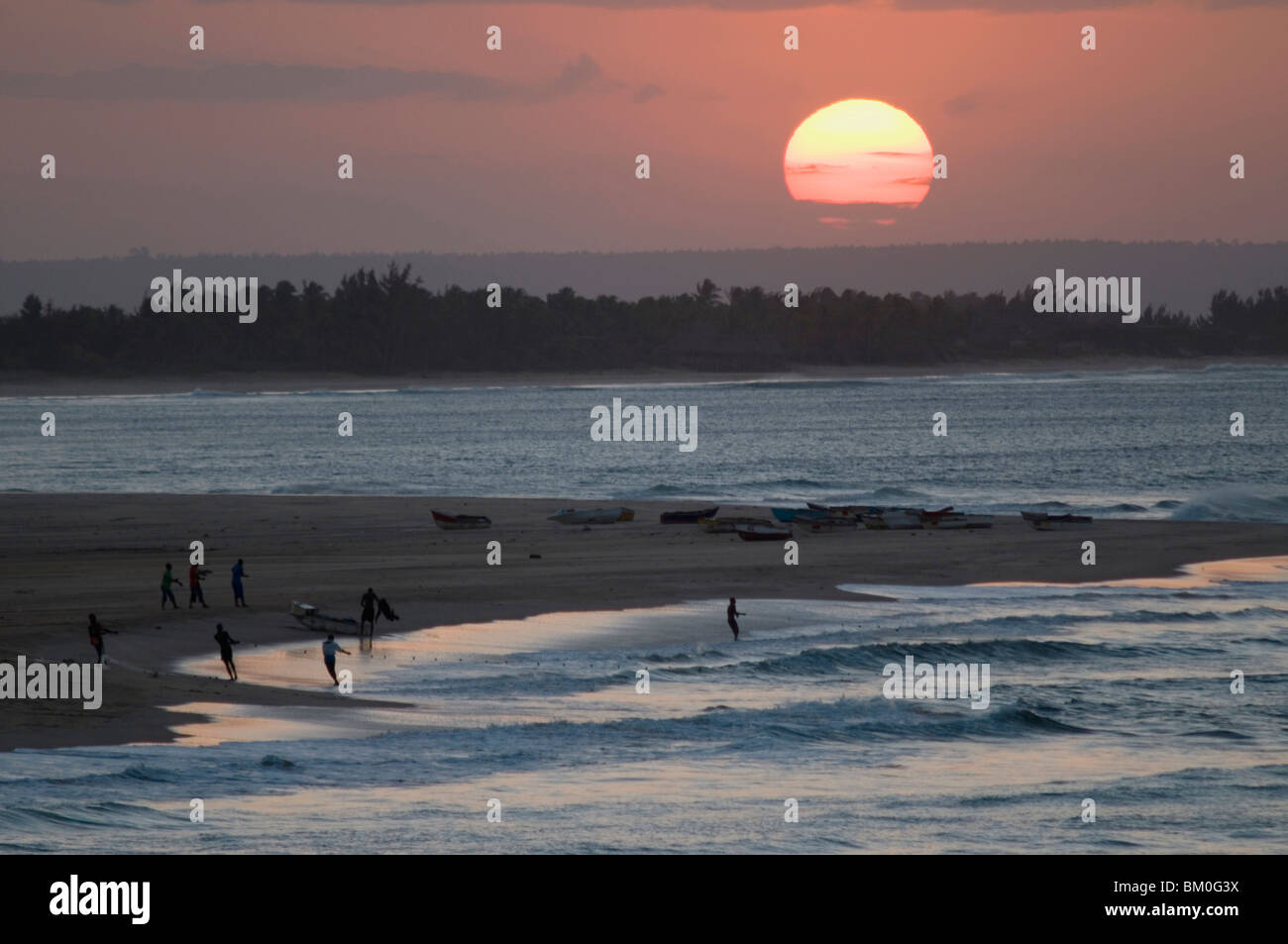 Fishermen pulling in net from shore at sunset, Barra, Inhambane Province, Mozambique Stock Photo