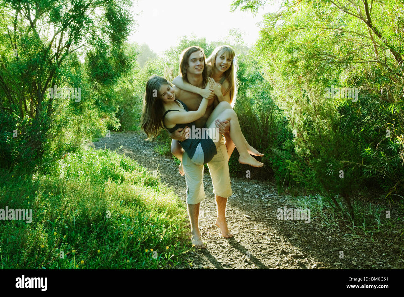 Young man carrying two young women Stock Photo Alamy