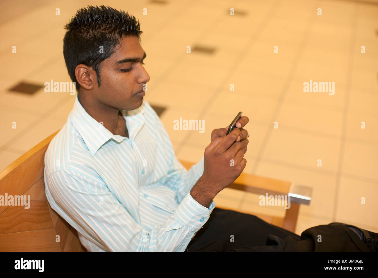 Man playing on cell phone in mall, KwaZulu Natal Province, South Africa Stock Photo