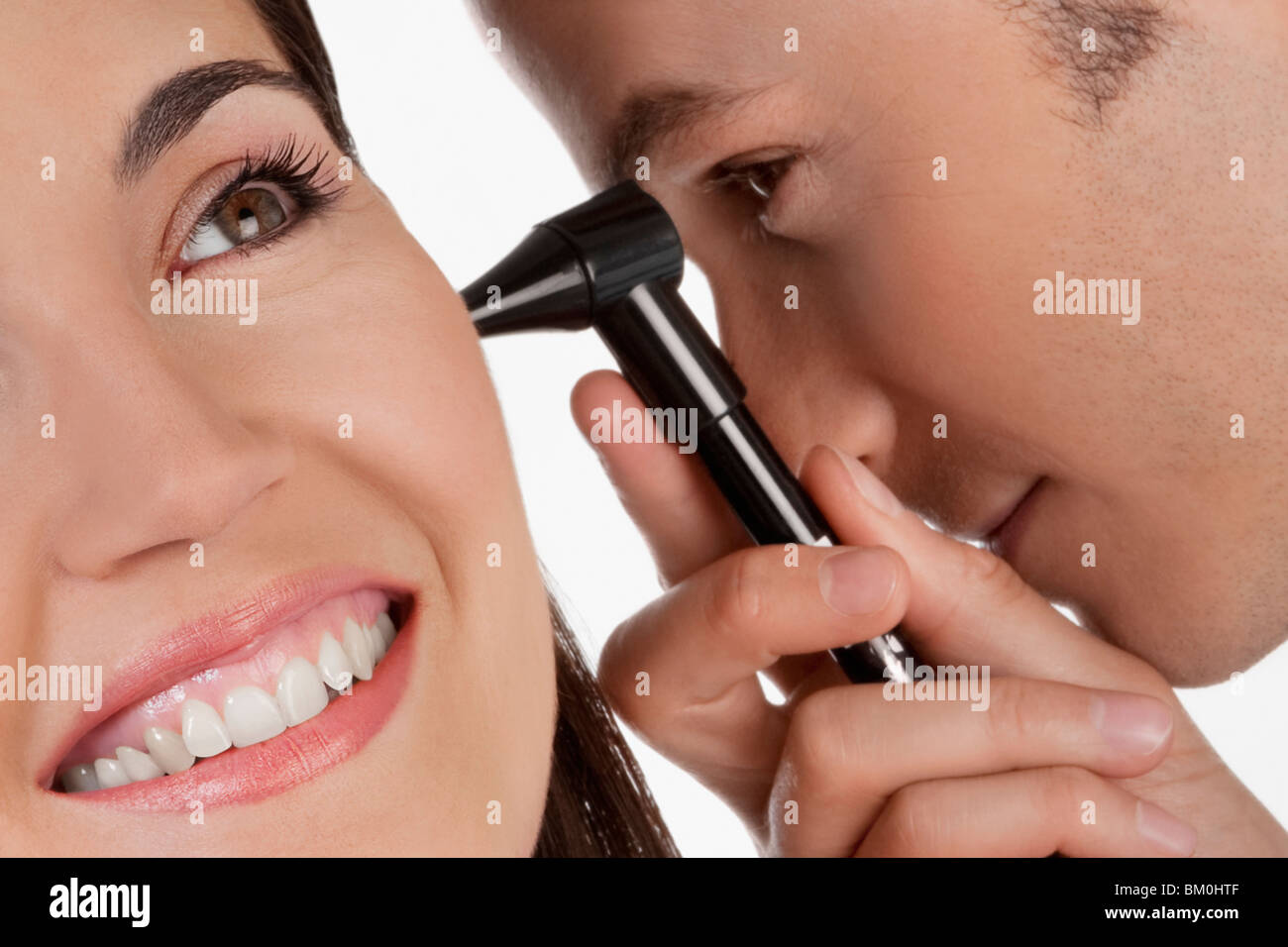 Doctor checking a woman's ear with an otoscope Stock Photo