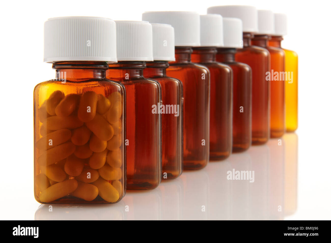 row of bottles with pills in the front container on white background Stock Photo
