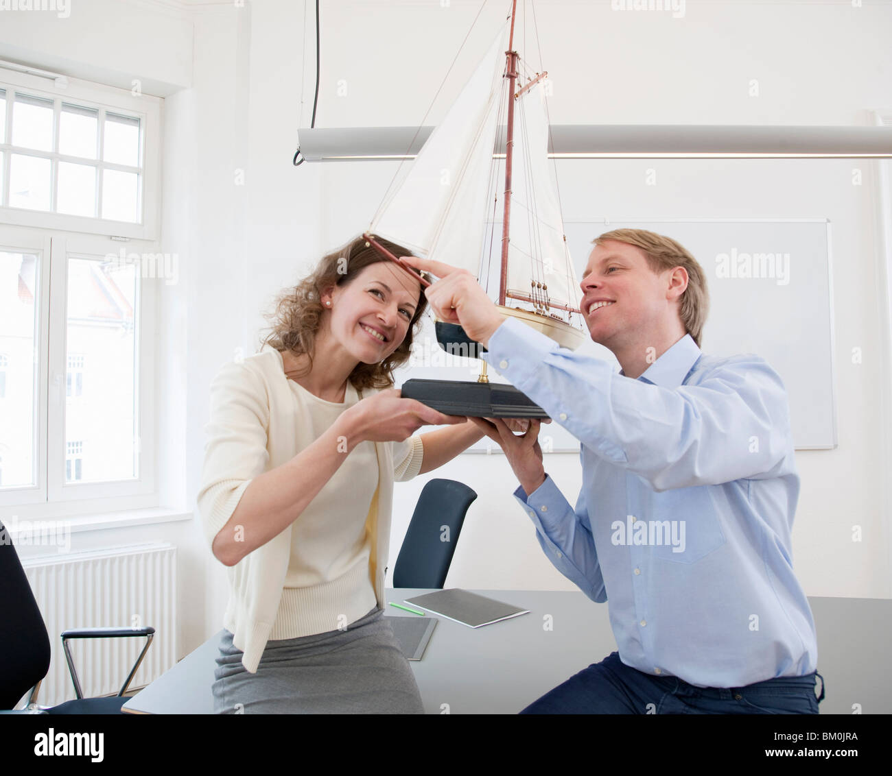 Businesspeople looking at model ship Stock Photo