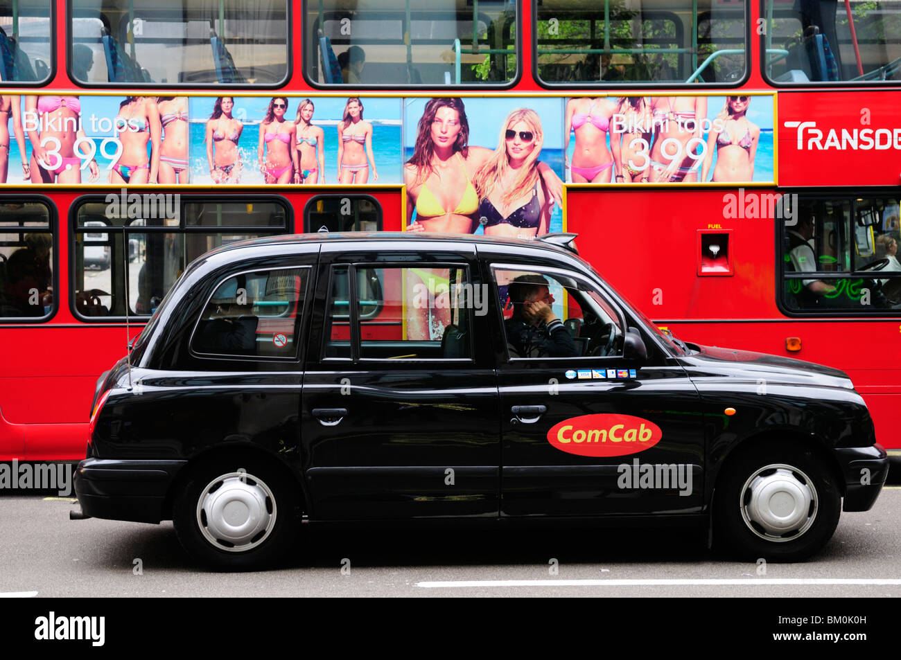 ComCab London Taxi and  Red Bus with  H&M Bikini advertisement, Oxford Street, London, England, UK Stock Photo
