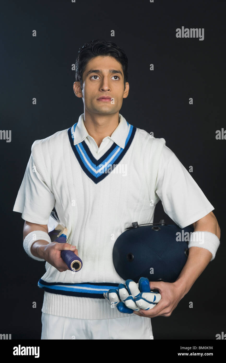 Cricket batsman holding a bat with a helmet and gloves Stock Photo Alamy