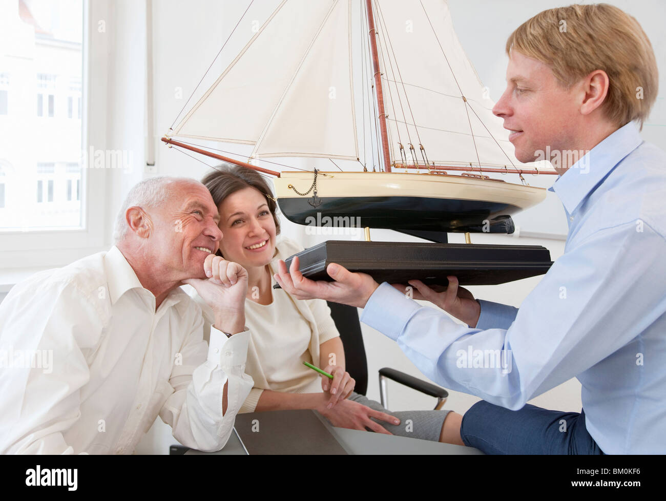 Businesspeople looking at model ship Stock Photo