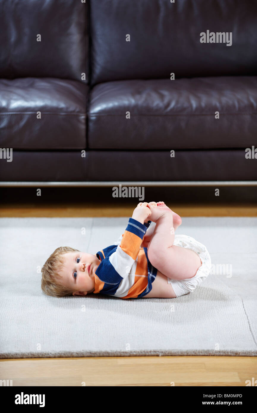 8 month old baby in diaper lying on rug Stock Photo