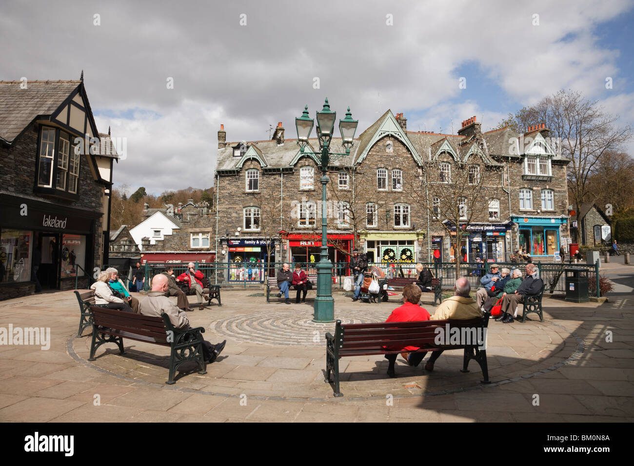 People sitting in the town square in Market Cross, Ambleside, Cumbria, England, UK, Britain Stock Photo