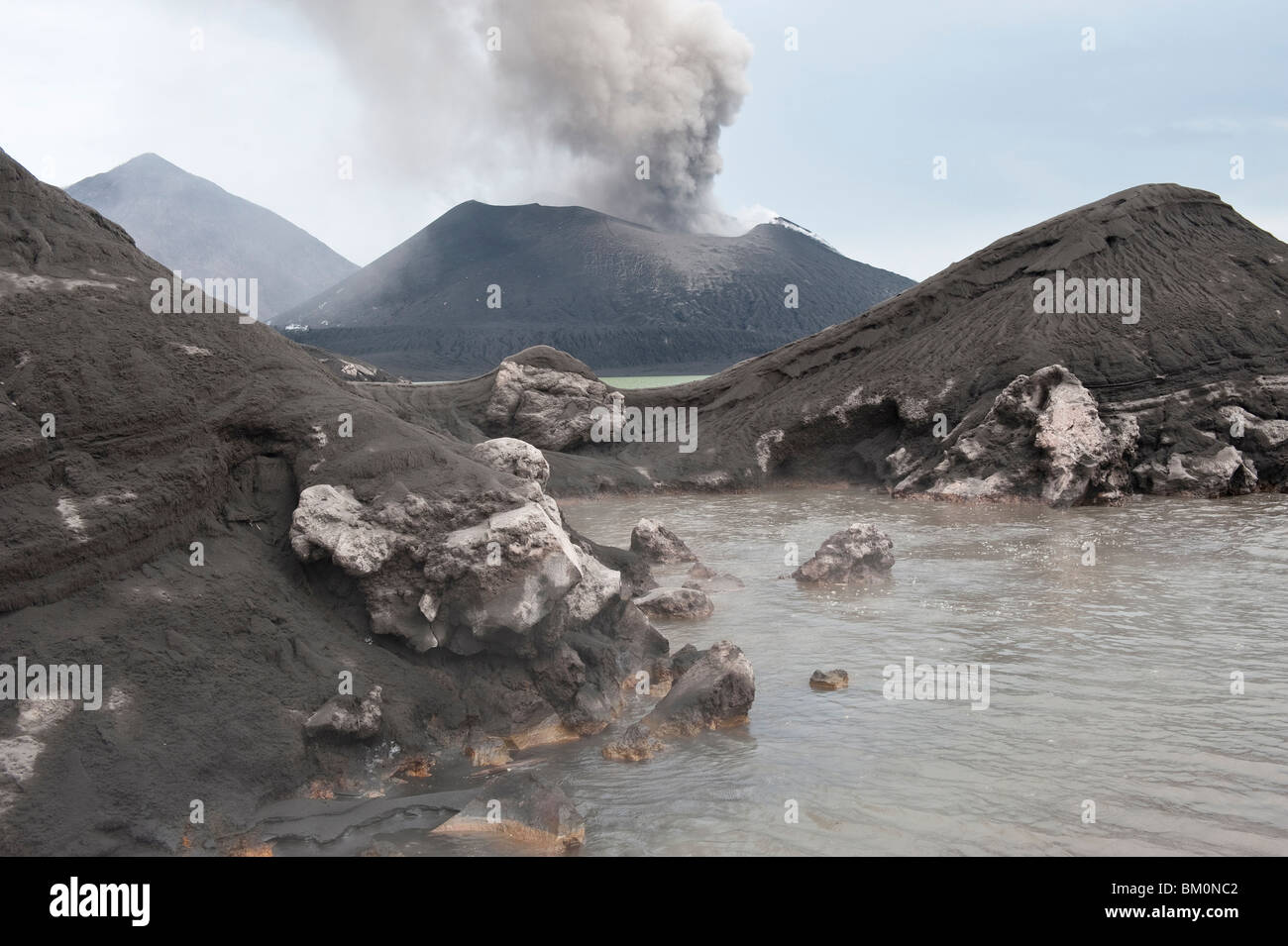 A Hot Volcanic Spring and Volcano Tavurvur Erupting a Plume of Ash in