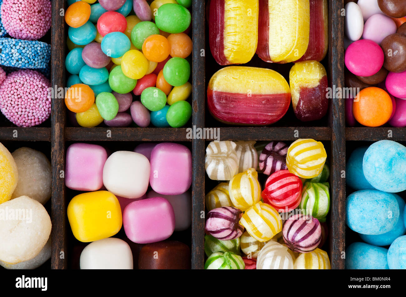 Colourful assorted childrens sweets and candy in a wooden tray Stock Photo