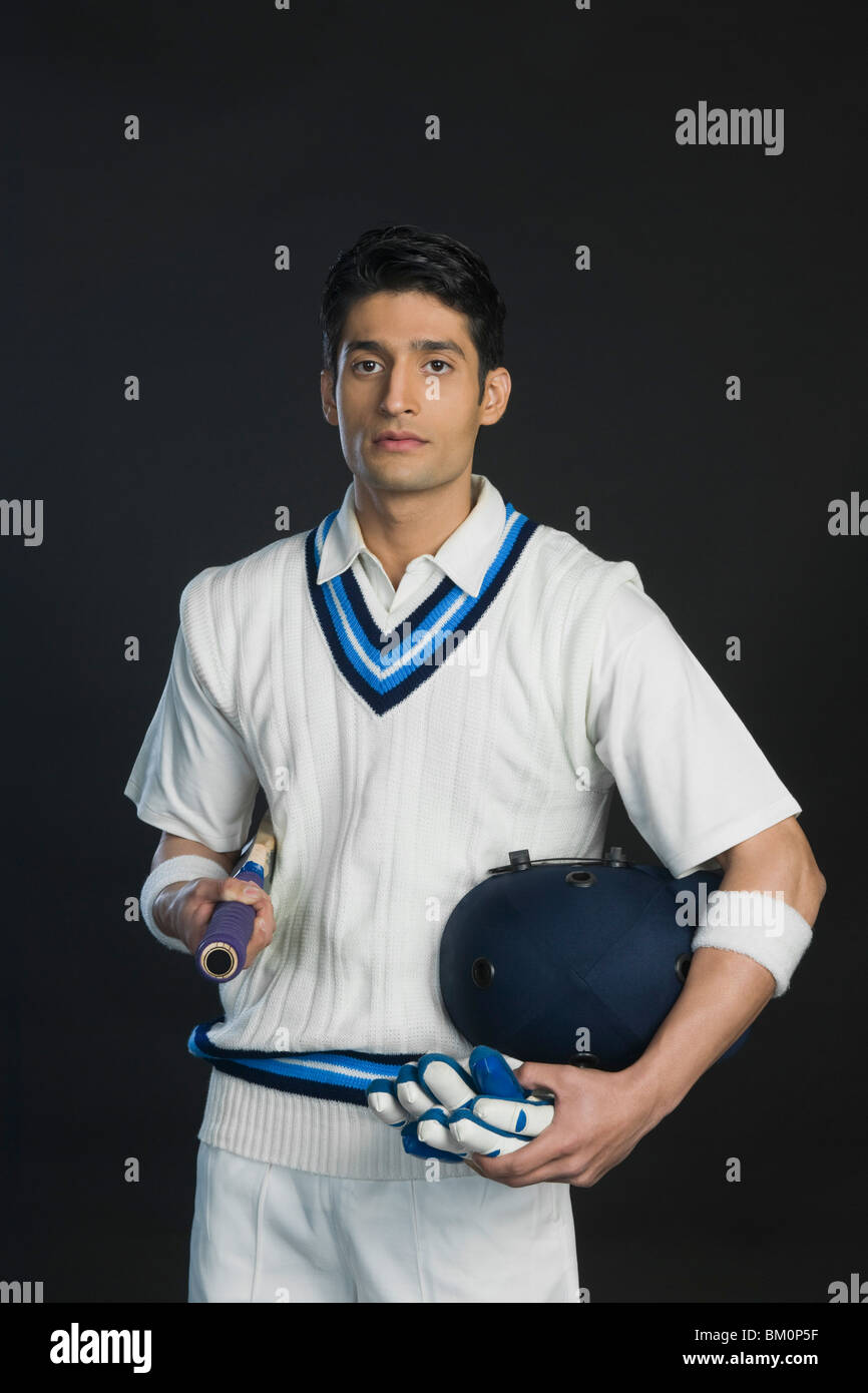 Cricket batsman holding a bat with a helmet and gloves Stock Photo Alamy