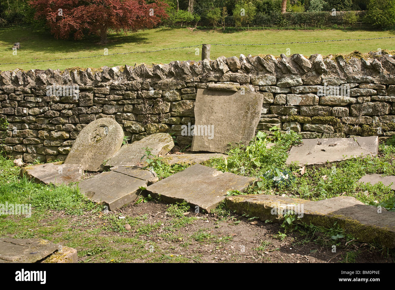 Broken gravestones laid in a corner of a churchyard. Stock Photo