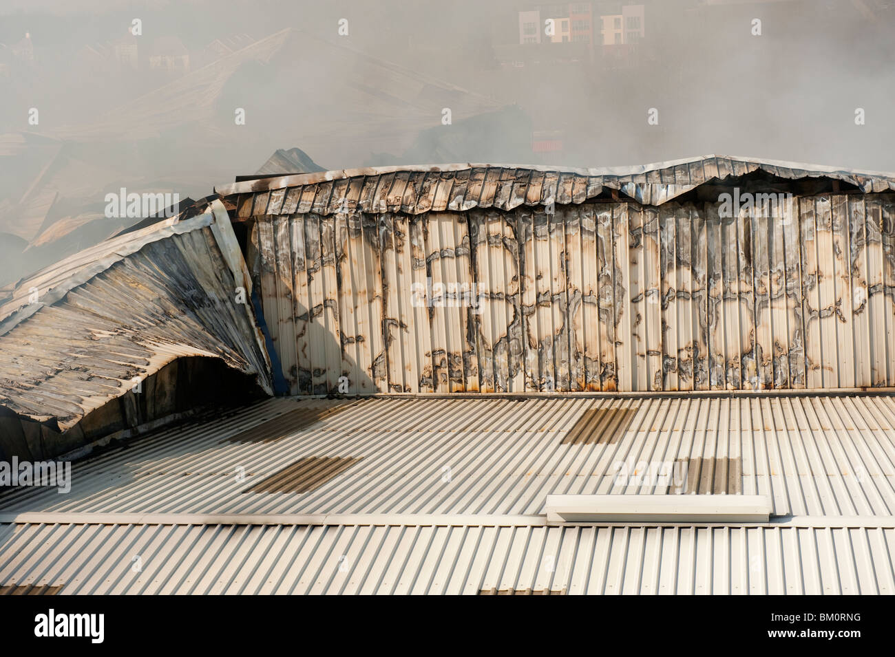 Large factory and warehouse collapsed and smoldering following major fire night before - Fire Brigade damping down Stock Photo