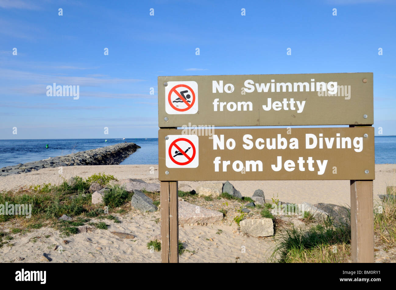 Wooden no swimming or scuba diving signs posted at jetty  near a sandy beach in Sandwich, Cape Cod USA Stock Photo