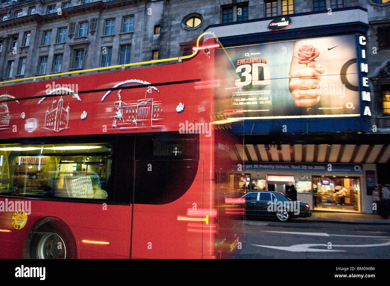 London open top tourist bus passing with movement in front of the Cineworld, Haymarket, in the West End, central London. Stock Photo