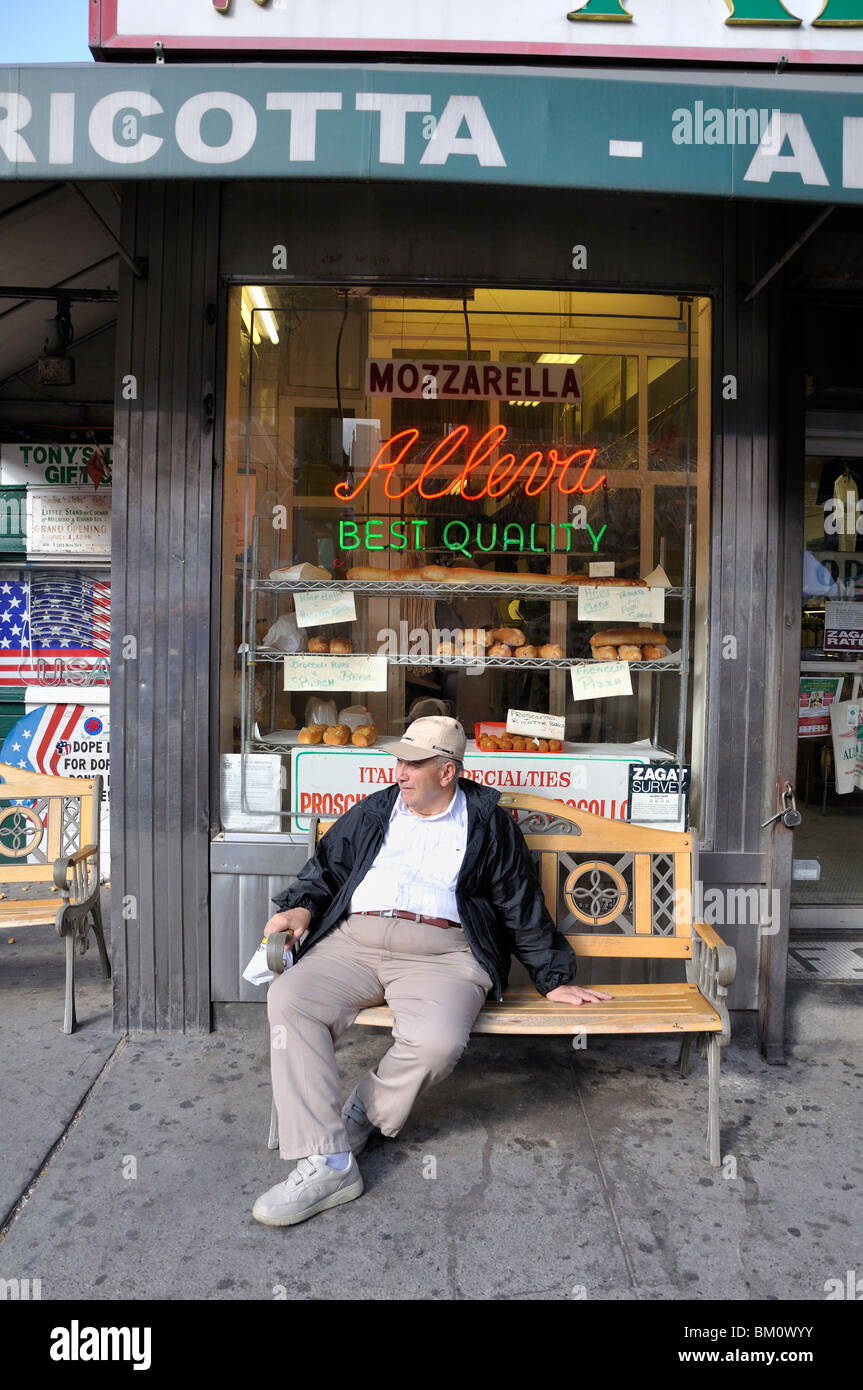 Italian man sitting on a bunch in front of a cheese store in Little Italy. Stock Photo