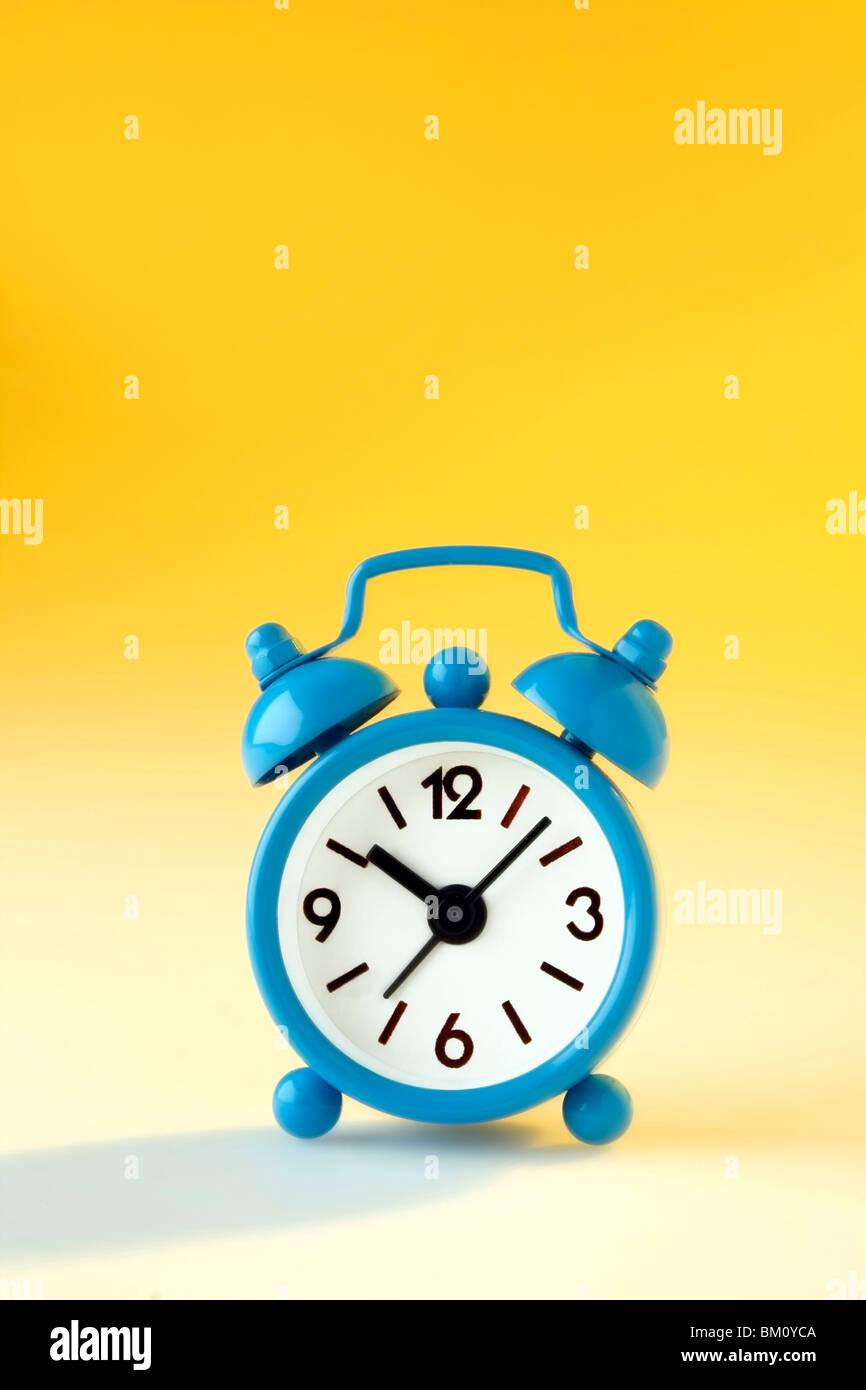 3d Rendering Of A Cheerful Alarm Clock Mascot Holding A Sleek Mobile Phone  With An Empty