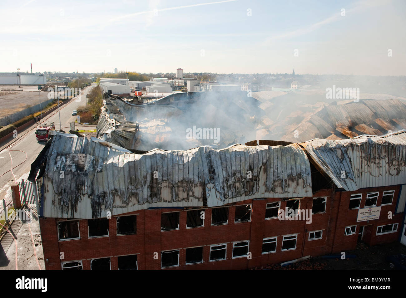 Large factory and warehouse collapsed and smoldering following major fire night before - Fire Brigade damping down Stock Photo