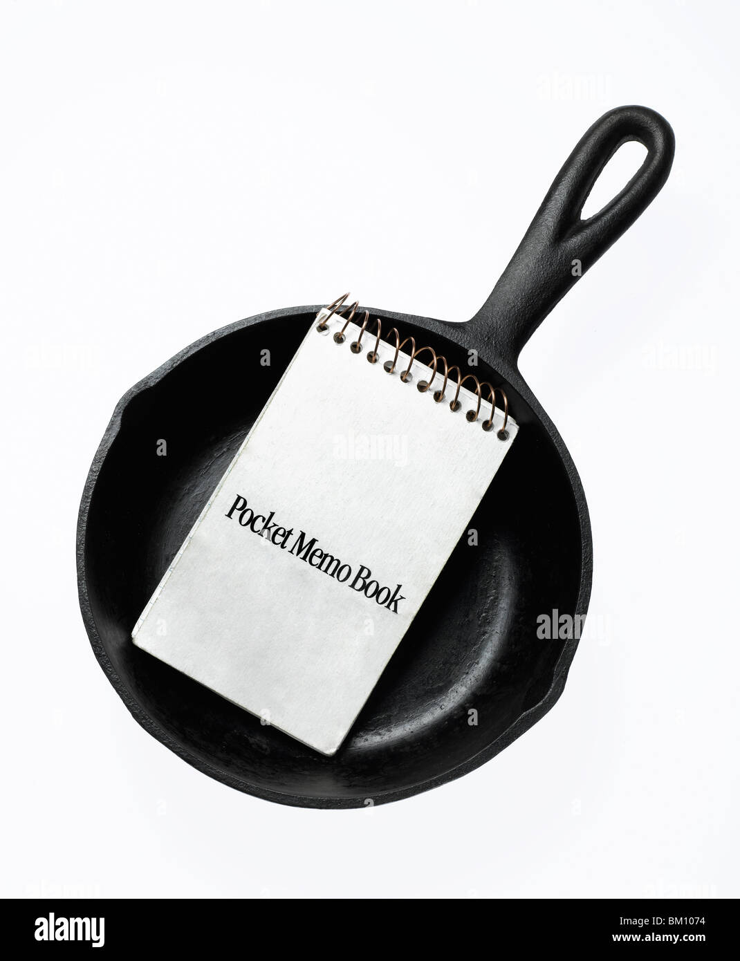 black cast iron fry pan with note book on white background Stock Photo
