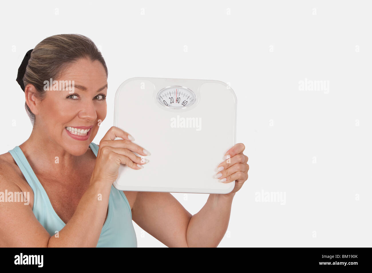 Portrait of a woman holding a bathroom scale and smiling Stock Photo