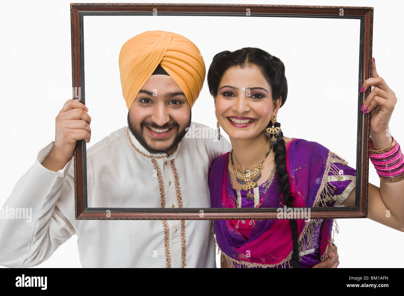 Portrait of a Sikh couple holding a picture frame and smiling Stock Photo