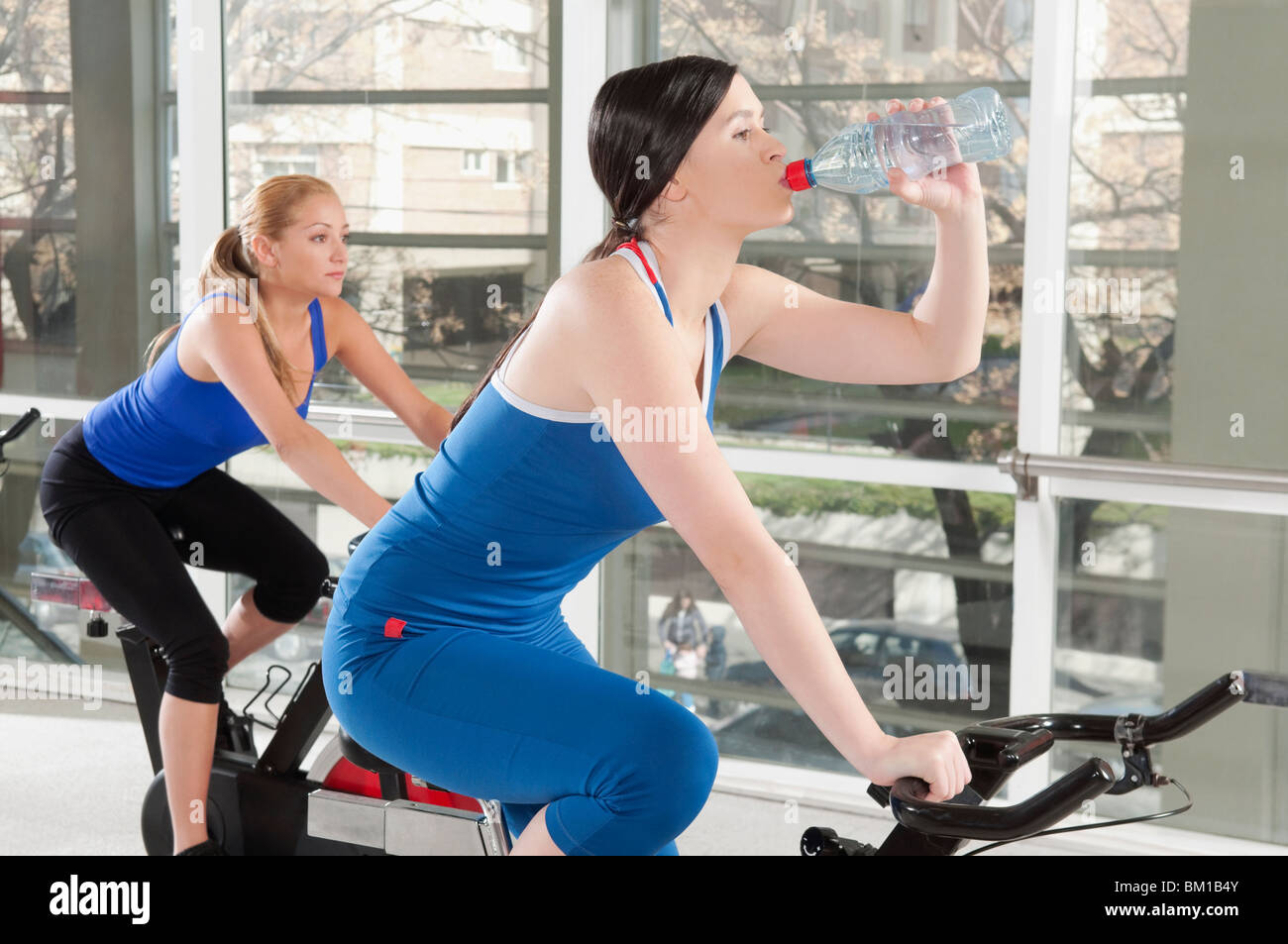Woman drinking water and working out with another woman in a gym Stock Photo