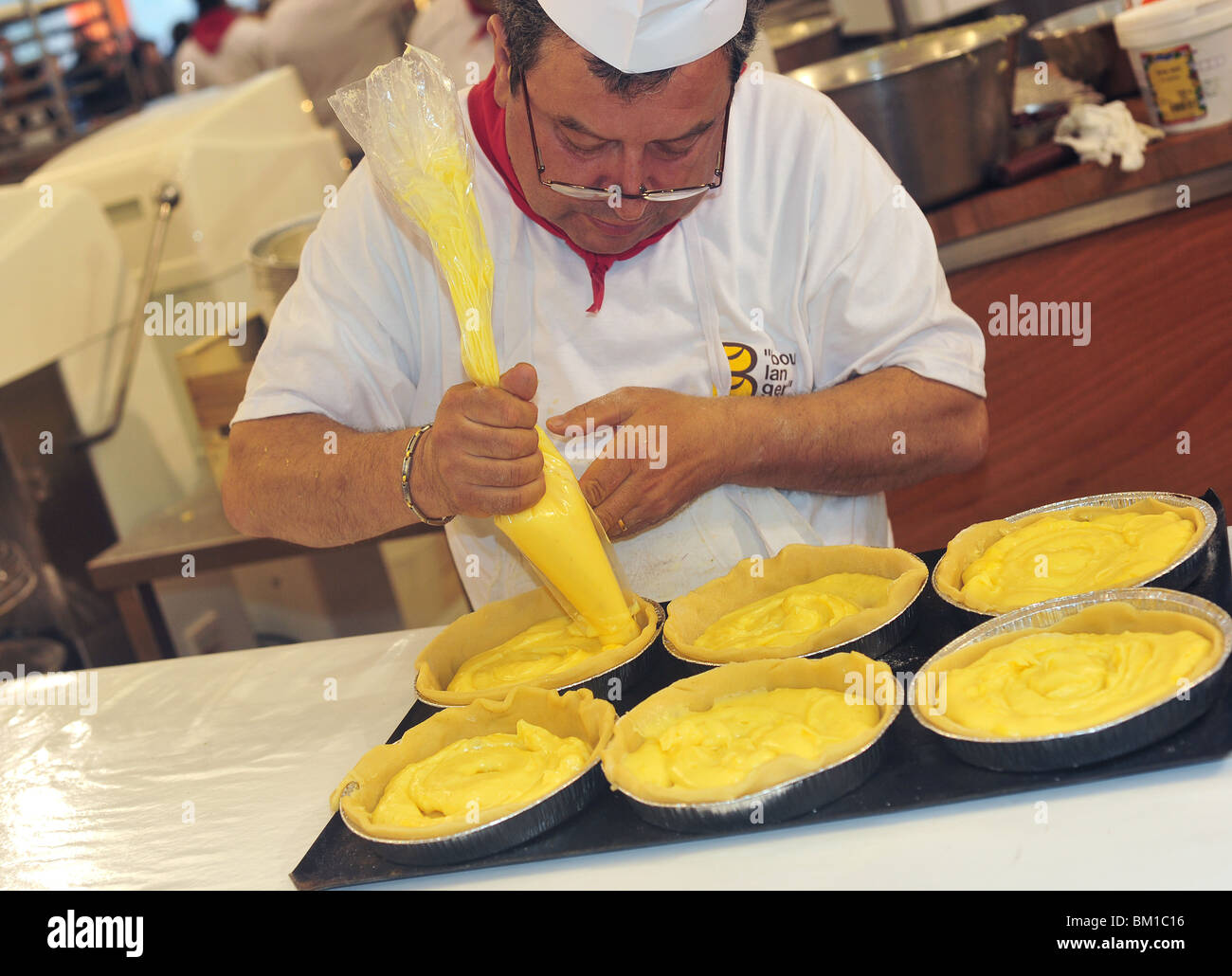 confectioner squeezing cream in cakes Stock Photo