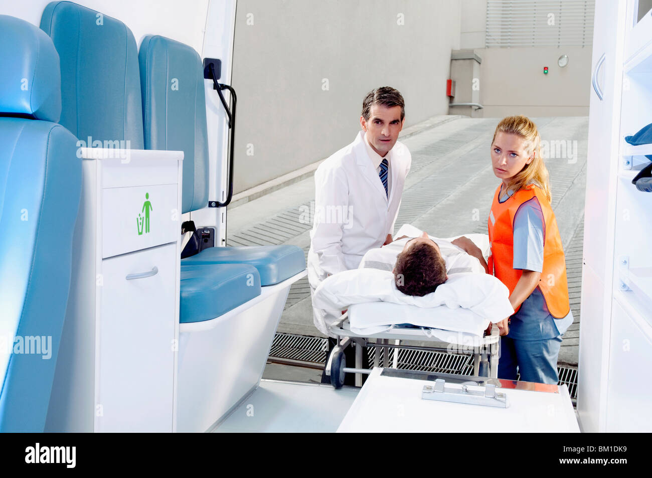 Paramedics pushing a patient on a gurney from an ambulance Stock Photo