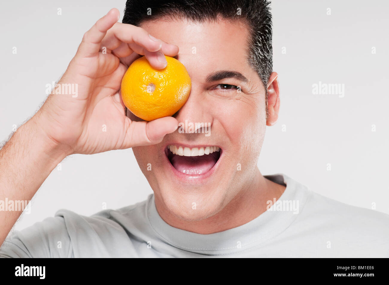 Man covering his eye with an orange Stock Photo